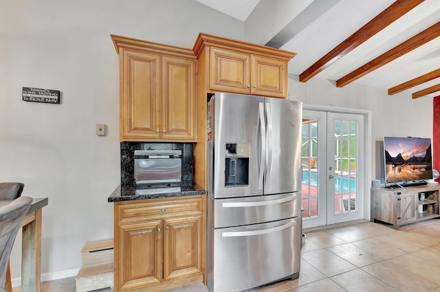 kitchen featuring light tile patterned floors, dark stone counters, french doors, stainless steel refrigerator with ice dispenser, and beam ceiling