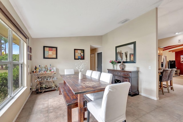 dining room with lofted ceiling, visible vents, plenty of natural light, and light tile patterned floors