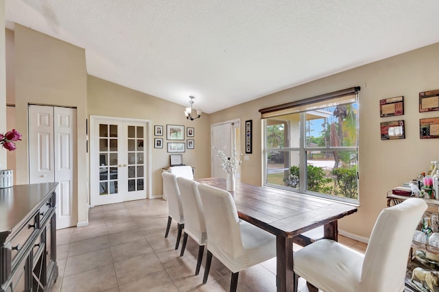 dining room with french doors, light tile patterned floors, lofted ceiling, an inviting chandelier, and a textured ceiling