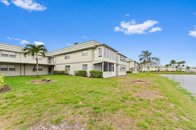 rear view of house with a yard, a water view, and a residential view