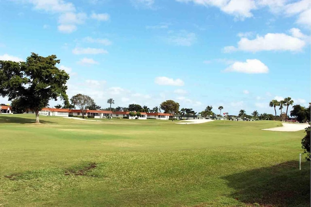 view of home's community featuring view of golf course and a yard