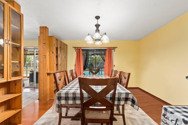 dining space with a chandelier, baseboards, and wood finished floors