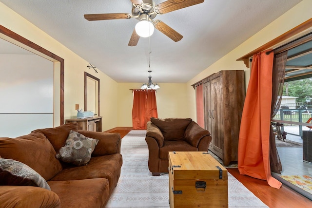 living room with light wood-type flooring, a textured ceiling, and ceiling fan with notable chandelier