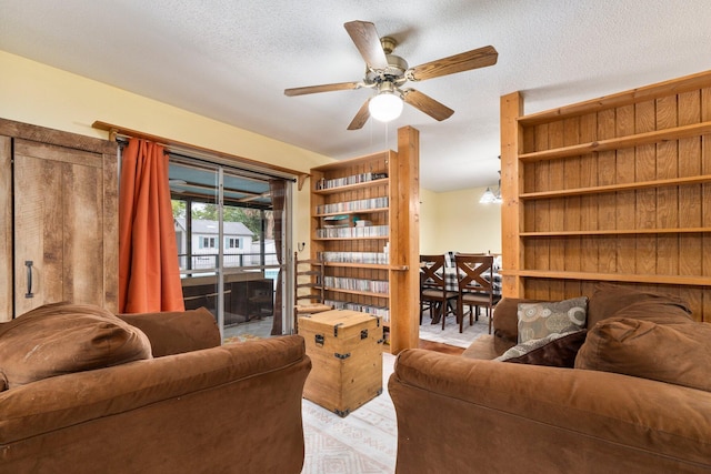 living room featuring light wood-style flooring, ceiling fan, and a textured ceiling