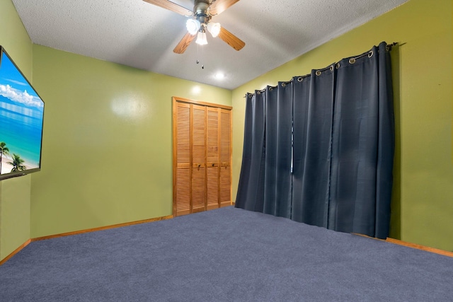 carpeted spare room with a ceiling fan, a textured ceiling, and baseboards