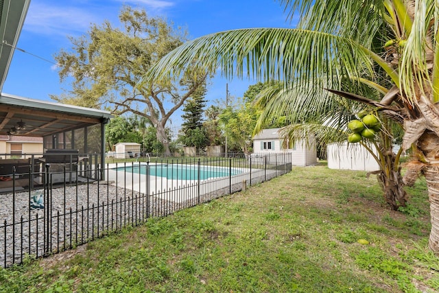 view of swimming pool featuring an outbuilding, a patio, fence, a lawn, and a fenced in pool