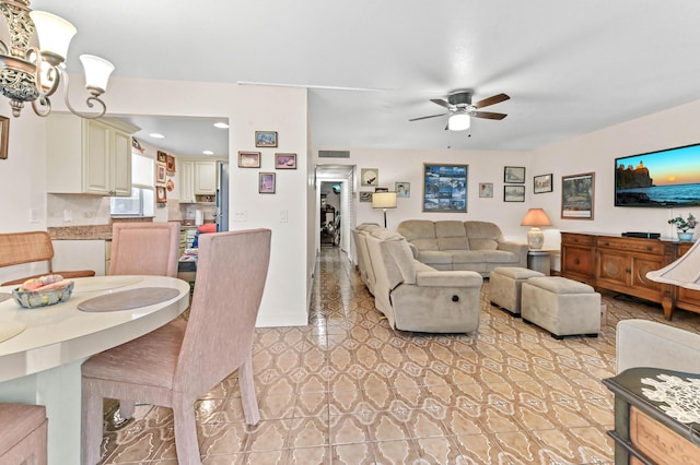 living area with light tile patterned floors, visible vents, baseboards, and ceiling fan with notable chandelier