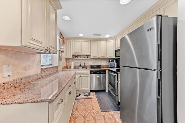 kitchen featuring tasteful backsplash, light stone countertops, stainless steel appliances, cream cabinetry, and recessed lighting