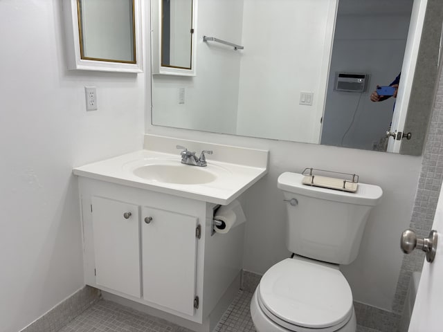 bathroom featuring tile patterned flooring, an AC wall unit, vanity, and toilet