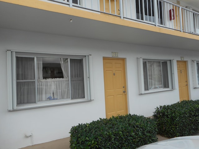 property entrance featuring a balcony and stucco siding