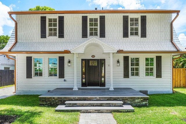 view of front of house featuring a porch, fence, and a front lawn