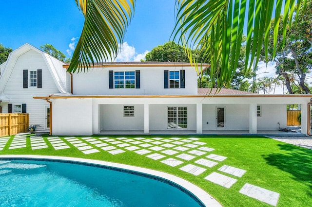 rear view of house featuring fence, an outdoor pool, a patio, and a yard