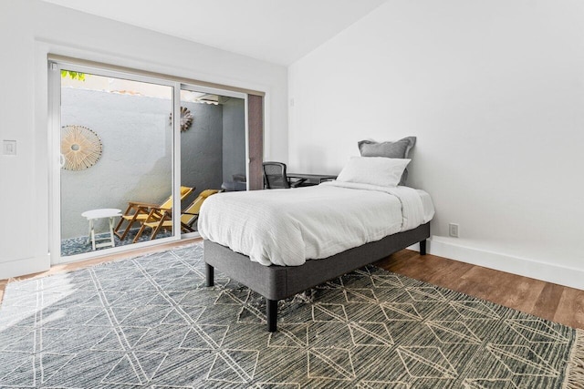 bedroom with vaulted ceiling, wood finished floors, and baseboards