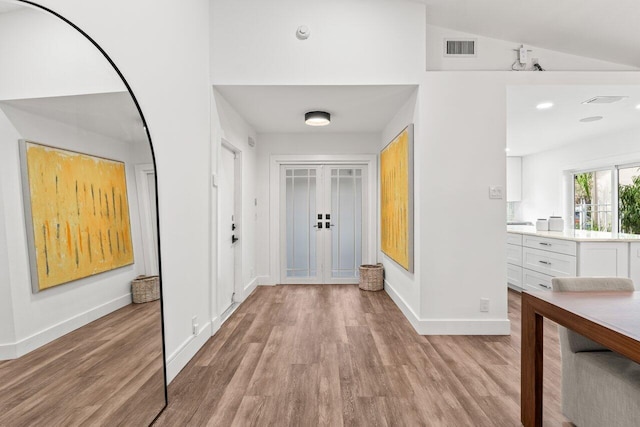 interior space featuring baseboards, visible vents, lofted ceiling, french doors, and light wood-style floors