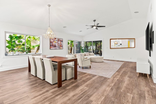 dining space featuring baseboards, vaulted ceiling, wood finished floors, and ceiling fan with notable chandelier