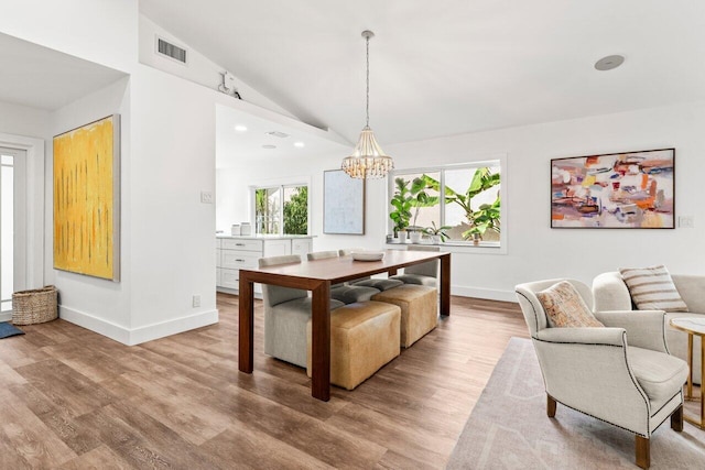 dining room featuring visible vents, baseboards, lofted ceiling, an inviting chandelier, and light wood-style floors