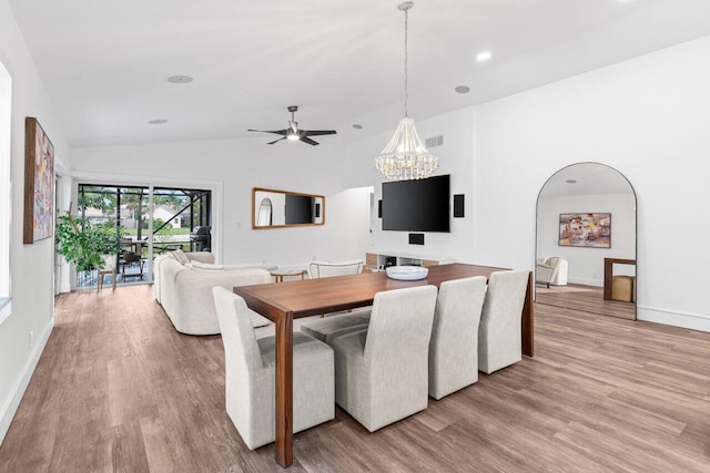 dining area with arched walkways, visible vents, vaulted ceiling, wood finished floors, and baseboards