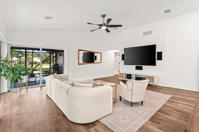 living room with ceiling fan, wood finished floors, visible vents, baseboards, and vaulted ceiling