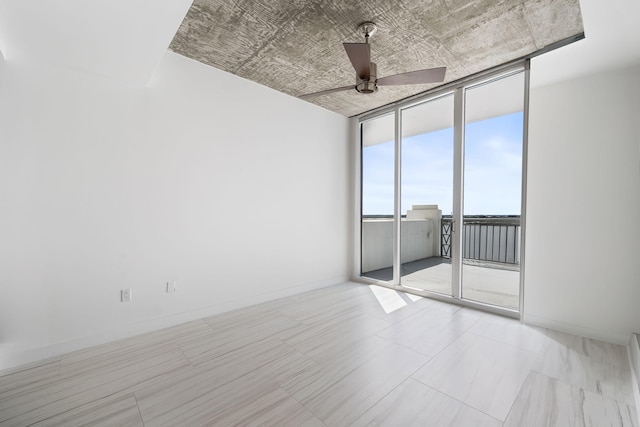 empty room featuring a wall of windows, a ceiling fan, and baseboards