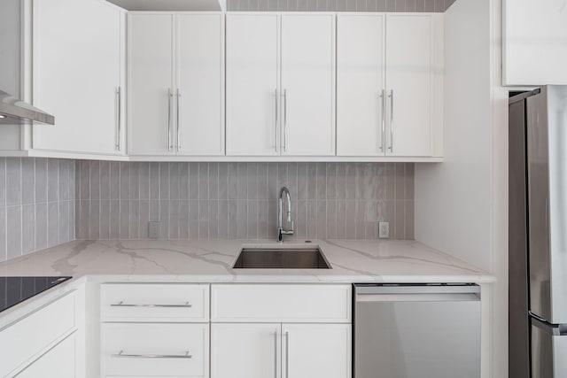 kitchen with stainless steel appliances, white cabinetry, a sink, and backsplash