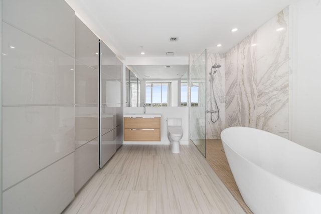 full bath with tile walls, a marble finish shower, a soaking tub, toilet, and vanity