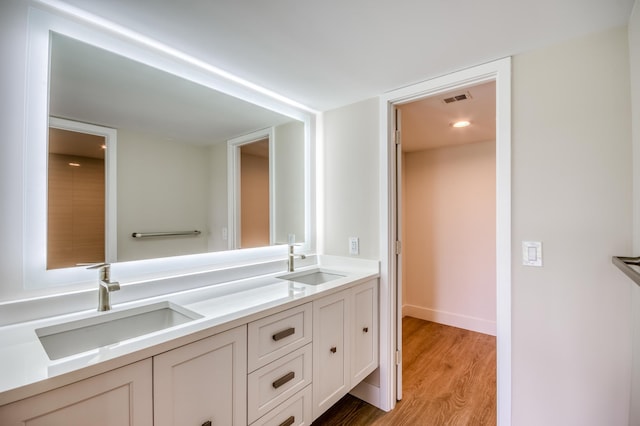 bathroom featuring double vanity, wood finished floors, a sink, and visible vents