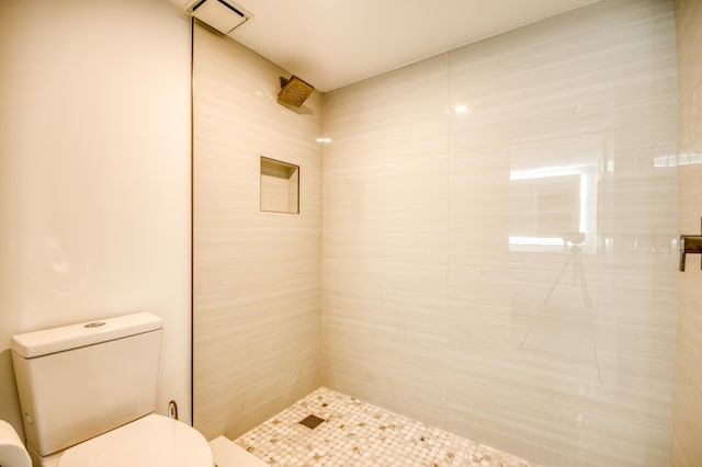 full bath with toilet, visible vents, and a tile shower