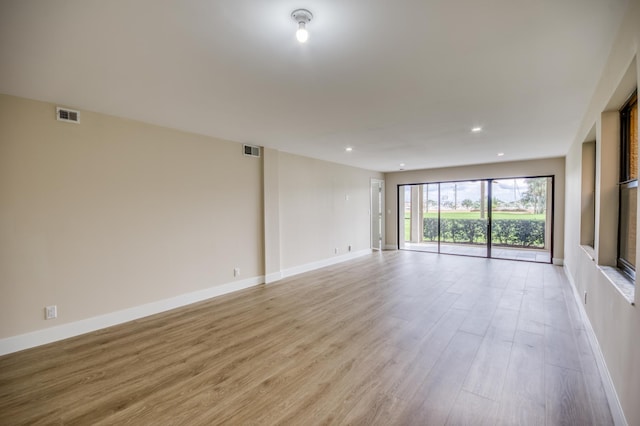 spare room with light wood-style flooring, visible vents, and baseboards