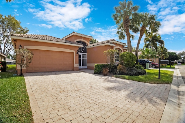 mediterranean / spanish-style home with a garage, decorative driveway, a tile roof, and stucco siding