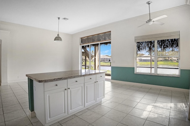 kitchen featuring a water view, white cabinetry, a center island, decorative light fixtures, and crown molding