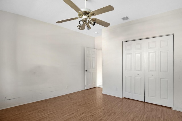 unfurnished bedroom with a ceiling fan, a closet, visible vents, and wood finished floors