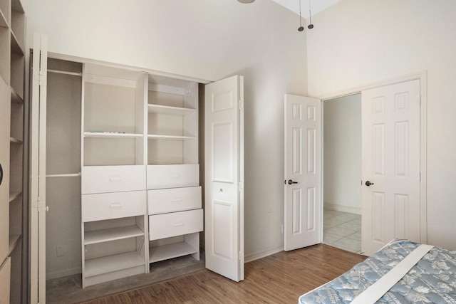 bedroom featuring wood finished floors, a towering ceiling, and baseboards