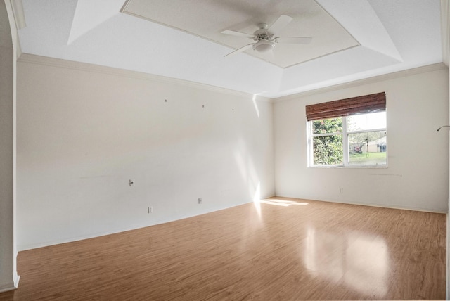 spare room with ceiling fan, a tray ceiling, wood finished floors, and crown molding