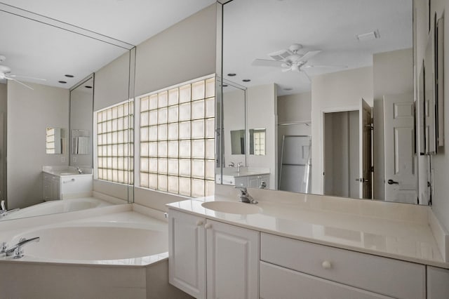 bathroom with a bath, ceiling fan, two vanities, and a sink