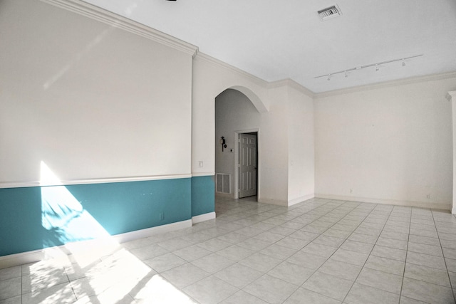 empty room with light tile patterned flooring, visible vents, arched walkways, and ornamental molding