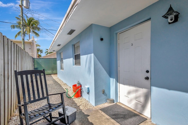 entrance to property with fence and stucco siding