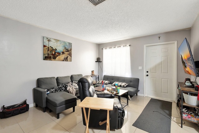 living room featuring baseboards, visible vents, a textured ceiling, and light tile patterned flooring