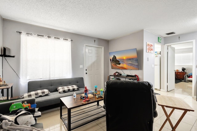 living room with visible vents, a textured ceiling, and light tile patterned floors