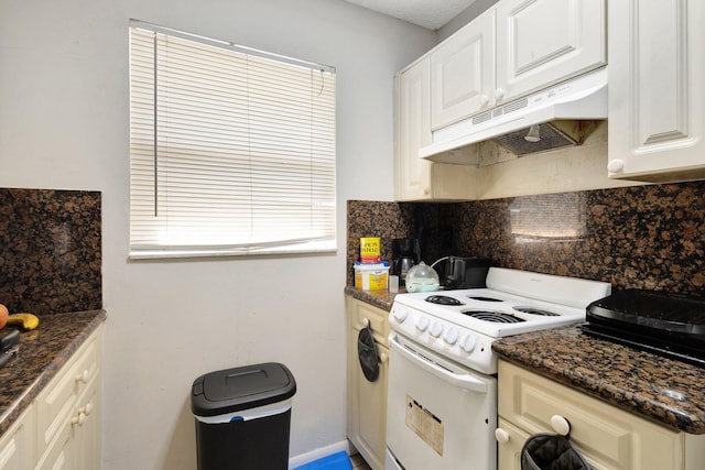 kitchen featuring under cabinet range hood, white cabinetry, tasteful backsplash, white range with electric cooktop, and dark stone countertops