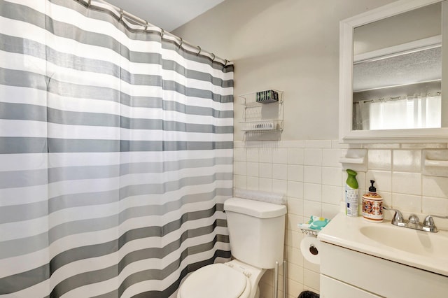 full bath featuring tile walls, toilet, wainscoting, a textured ceiling, and vanity