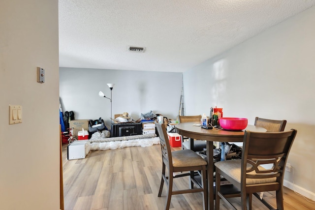 dining room with visible vents, a textured ceiling, and light wood finished floors