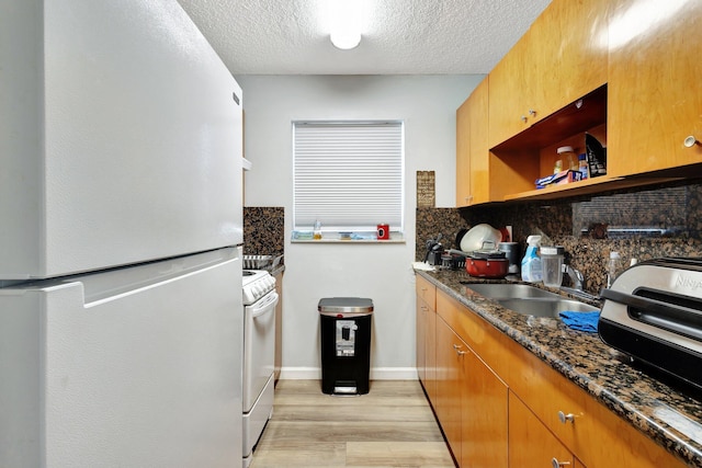 kitchen with open shelves, decorative backsplash, a sink, dark stone countertops, and white appliances