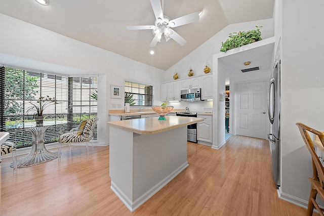 kitchen featuring stainless steel appliances, light countertops, light wood finished floors, and white cabinetry