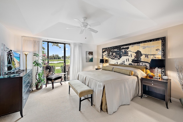 bedroom with light carpet, a tray ceiling, and a ceiling fan