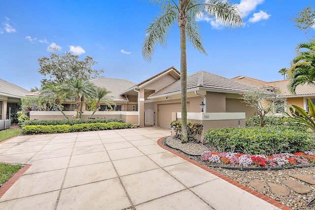 view of front of house with a garage, stucco siding, concrete driveway, and a tiled roof