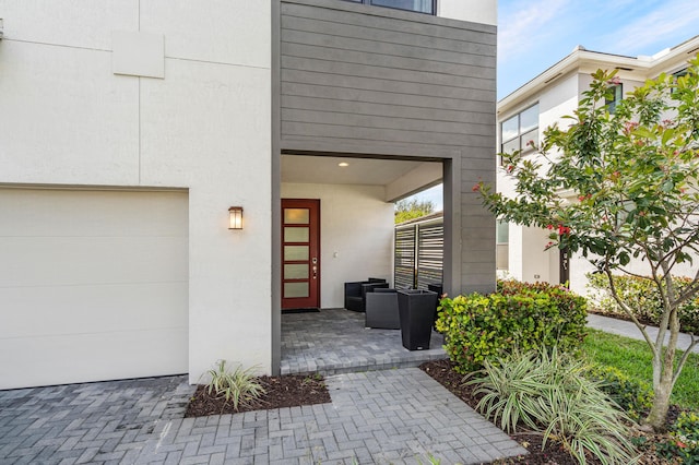 property entrance with a garage, a patio area, and stucco siding