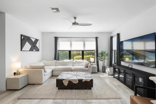 living room with wood finish floors, visible vents, and a ceiling fan