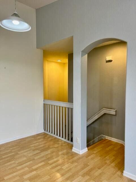 spare room featuring baseboards, arched walkways, and wood finished floors