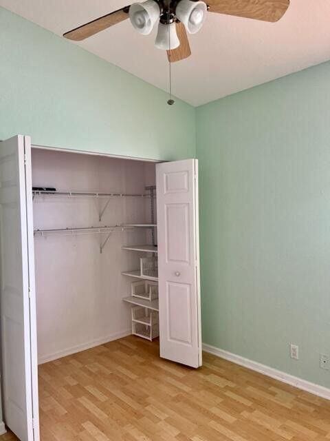 unfurnished bedroom featuring baseboards, ceiling fan, a closet, and light wood-style floors