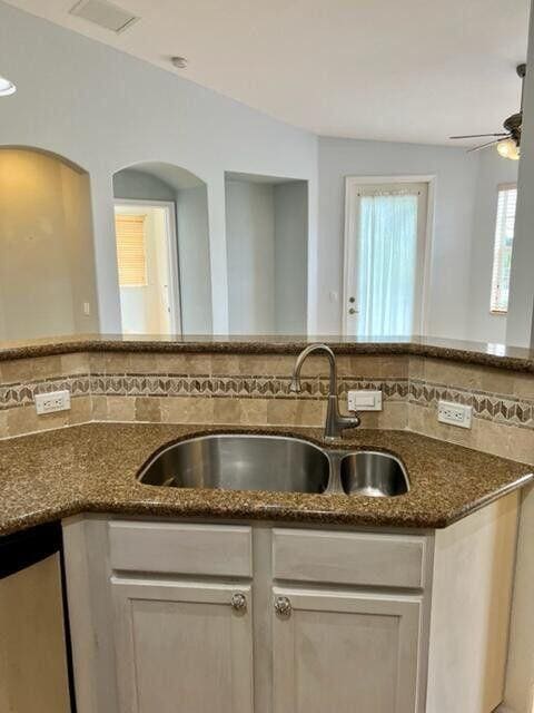 kitchen featuring dark stone countertops, visible vents, tasteful backsplash, and a sink